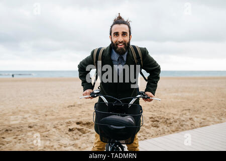 Ritratto di uomo felice con e-bike in spiaggia Foto Stock