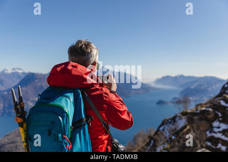 L'Italia, Como, uomo su una escursione in montagna sopra il lago di Como prendere foto con il telefono cellulare Foto Stock