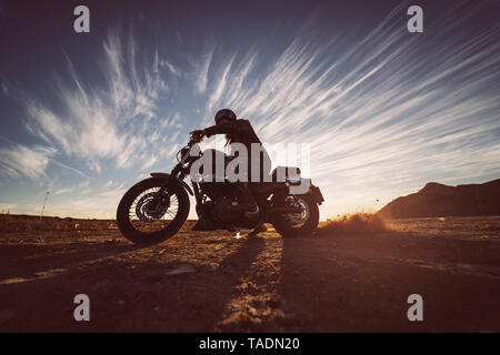 Uomo sulla moto in natura al tramonto Foto Stock