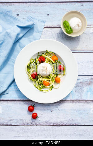 Tagliatelle di zucchine con pomodori al forno, burrata formaggio, pepe e olio di oliva Foto Stock