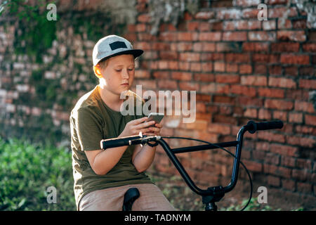 Ragazzo con la bmx bike tramite telefono cellulare Foto Stock