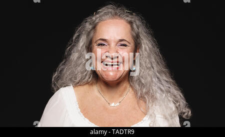 Close up allegro vecchia donna che guarda la fotocamera. Senior donna isolato su sfondo nero e ridere. Foto Stock