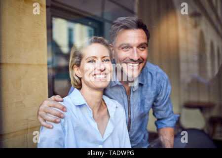 Ritratto di felice coppia dietro il vetro di finestra Foto Stock