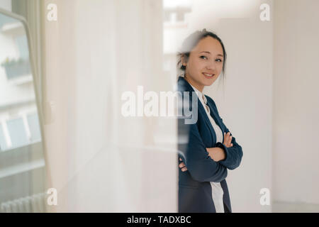 Ritratto di sorridente giovane donna in piedi con le braccia incrociate Foto Stock