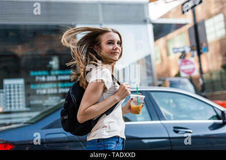 Giovane donna esplorare New York City, attraversando via Foto Stock