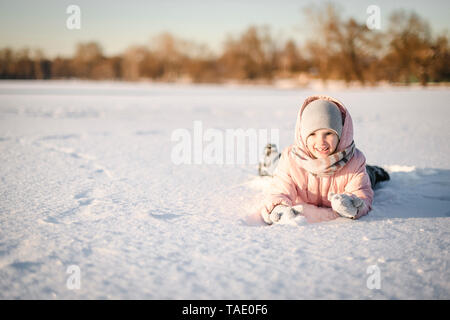 Ritratto di bambina giacente nel campo di neve Foto Stock