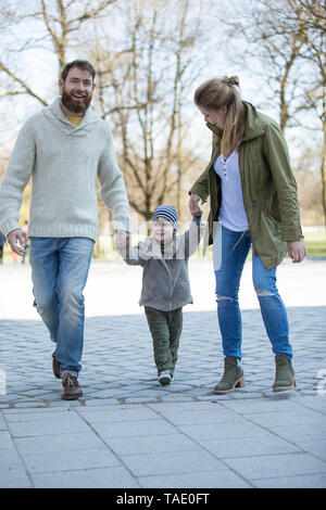 Genitori felici camminando mano nella mano con figlio Foto Stock