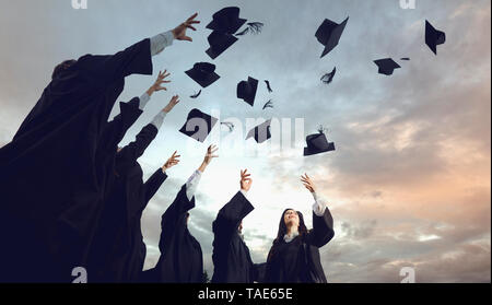 Un gruppo di laureati getta cappelli in cielo.la laurea.Università gesto e concetto di persone. Foto Stock