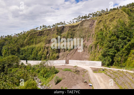 Strada con recinzioni in cemento sull'isola di Camiguin, Filippine. Protezione della strada da frane e frane. Il crollo del suolo sulla strada nelle alture. Foto Stock