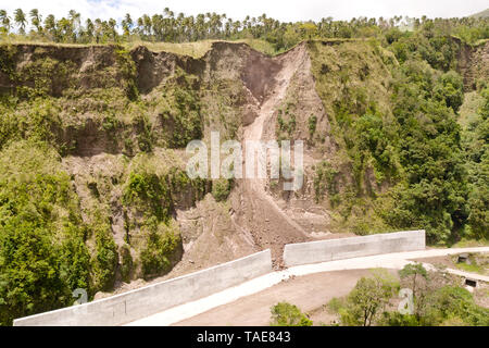 Strada con recinzioni in cemento sull'isola di Camiguin, Filippine. Protezione della strada da frane e frane. Il crollo del suolo sulla strada nelle alture. Foto Stock