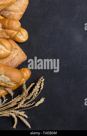 La gamma di tipi di pane fresco con grano. Su sfondo scuro. Spazio libero, vista dall'alto, laici piatta Foto Stock