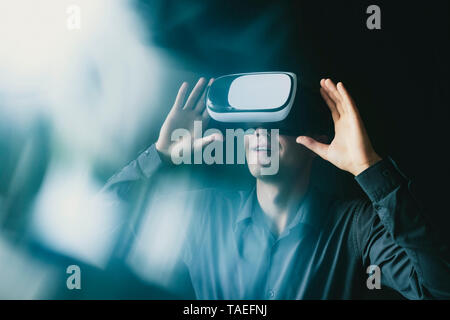 Immagine composita di un uomo che indossa una cuffia VR interagente con una simulazione di realtà virtuale ambiente con luce flare Foto Stock
