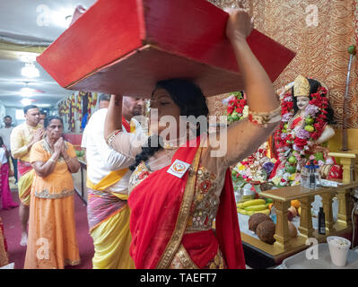 A sua madre (arancione) Servizio di ringraziamento una giovane donna Indù porta offerte per le divinità in un tempio in Ozone Park, Queens, a New York City. Foto Stock