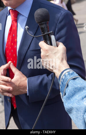 Giornalista tenendo il microfono rende media intervista con un imprenditore o politico Foto Stock