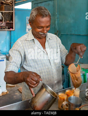 Ritratto verticale di un uomo che fa tè tradizionale o chai in India. Foto Stock
