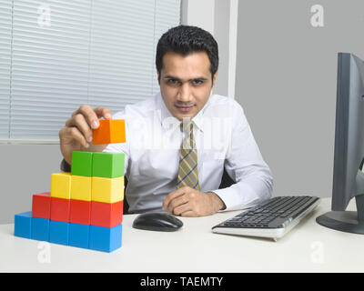 I dirigenti aziendali utilizzando blocchi di costruzione per costruire un edificio concettuale Foto Stock