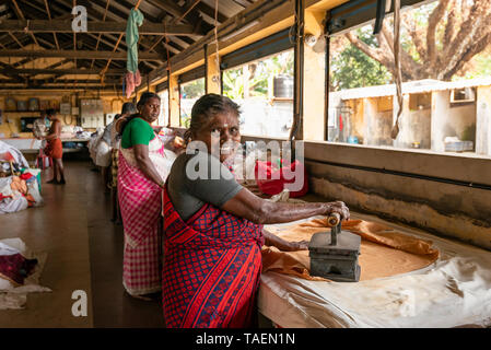 Ritratto orizzontale di dhobi wallahs a stirare e piegare i vestiti puliti in India. Foto Stock