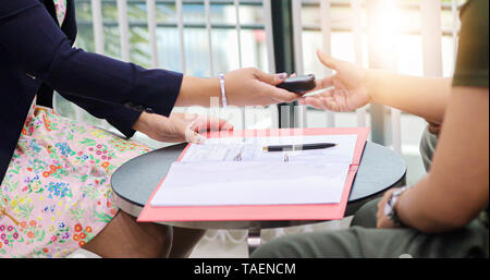 Agente donna è in possesso della chiave per auto in attesa di dare dopo imprenditori firmerà un auto contratto di acquisto. Foto Stock