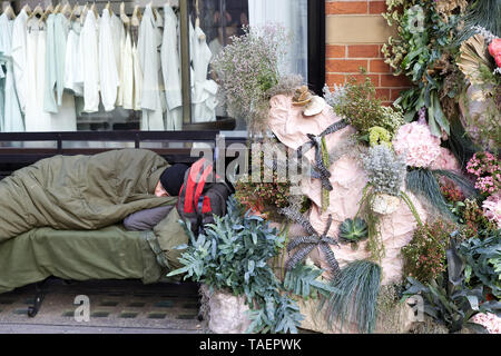 Chelsea in Fiore 2019, senzatetto in Chelsea, uomo dorme grezzo su una panchina accanto al display floreali Foto Stock