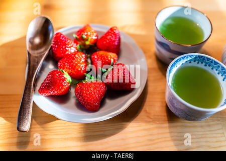 Tradizionale Giapponese di dessert plump costoso fragole sulla tavola di legno la piastra con il cucchiaio di legno e green tea cups Foto Stock