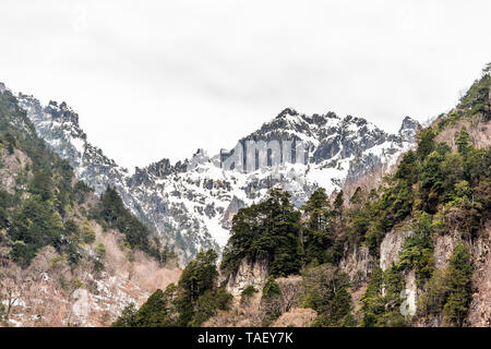 Picco di montagna con la neve in villaggi Okuhida Shinhotaka teleferica nella Prefettura di Gifu, Giappone park con cielo nuvoloso sul giorno di primavera Foto Stock