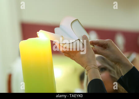 Zagabria, Croazia - 11 Maggio 2019 : dettaglio di una donna accensione candela sulla candela durante l omelia della Santa Messa di Prima Comunione nella Chiesa di San Nicola Vescovo Foto Stock