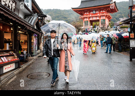 Kyoto, Giappone - Aprile 9, 2019: Coppia giovane tenendo le mani con ombrello durante la giornata piovosa camminando sulla strada vicino a Kiyomizu-dera tempio Foto Stock