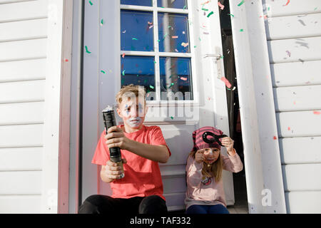 Fratello e sorella più piccola costituita per il carnevale seduto davanti la porta di entrata Foto Stock