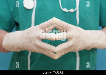 Chirurgo in verde frega tiene le mani insieme per spiegare i risultati della chirurgia Foto Stock