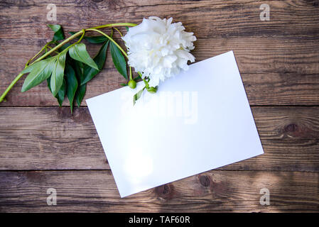 Bella bianca peonia ed il foglio di carta su sfondo di legno con spazio di copia Foto Stock