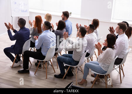 Spettatori seduti su una sedia in fila ad applaudire Speaker dopo la presentazione della conferenza Foto Stock