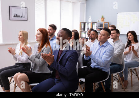 Spettatori seduti su una sedia in fila ad applaudire Speaker dopo la presentazione della conferenza Foto Stock