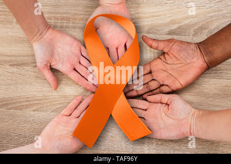 Vista in alzata di mano uniti nel cerchio tenendo il cancro uterino simbolo contro lo sfondo di legno Foto Stock