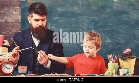Il padre e il Figlio insieme nel centro d'arte. Papà holding pennelli mentre kid è la scelta di colori. L'istruzione privata, concetto. Foto Stock