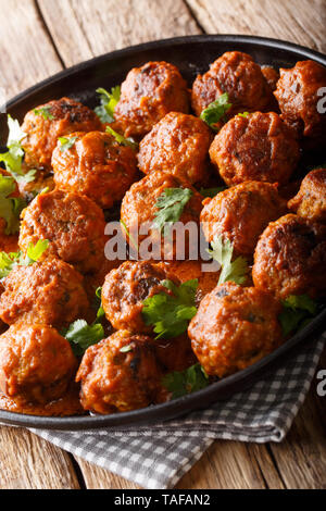 Pollo piccante polpette indonesiano sono complete in una noce di cocco cremosa salsa di curry close-up su una piastra sul tavolo. In verticale Foto Stock