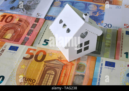 Piccola casa bianca su uno sfondo di banconote in euro. Foto Stock