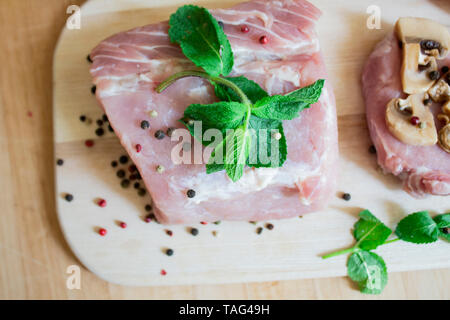 Carni bovine o bistecca di carne di maiale, carne macinata con pepe e menta sullo sfondo. Vista da sopra. Carni fresche per la cena o il pranzo. Carne alla brace. Cibo sano. c Foto Stock