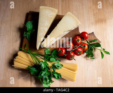 Gli spaghetti e la pasta sullo sfondo di legno. Il concetto di cottura. La pasta, di pomodori ciliegini, formaggio, menta e pektrushka. Vista da sopra. spazio copia Foto Stock