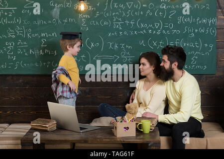 I genitori insegnare kid a casa. Ragazzo presentando la sua conoscenza a mamma e papà. I genitori in ascolto il loro figlio, lavagna su sfondo. Homeschooling concep Foto Stock