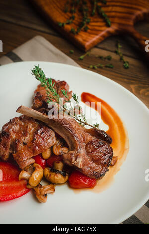 Costolette alla griglia con funghi, peperoni e timo. Cafe menu su un sfondo di legno in colori caldi con copia spazio. Foto Stock