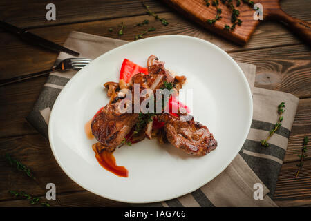 Costolette alla griglia con funghi, peperoni e timo. Cafe menu su un sfondo di legno in colori caldi con copia spazio. Foto Stock