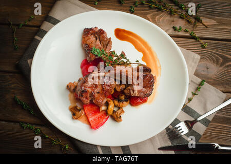 Costolette alla griglia con funghi, peperoni e timo. Cafe menu su un sfondo di legno in colori caldi con copia spazio. Foto Stock