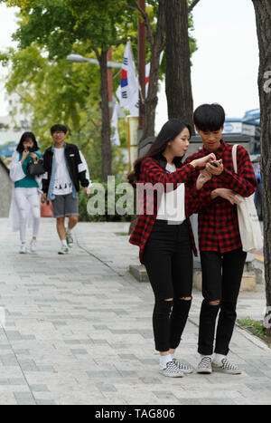 Un sud coreano giovane indossa dalla testa ai piedi matching outfit chatter su strada nei pressi del Palazzo Gyeongbokgung, Seoul, Corea del Sud. Foto Stock