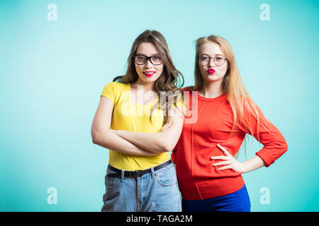 Felice positivo due ragazze eleganti abbracciando stand in prossimità della parete di blu. Close up ritratto divertente gioiosa attarctive giovani donne. comunicazione e amicizia Foto Stock