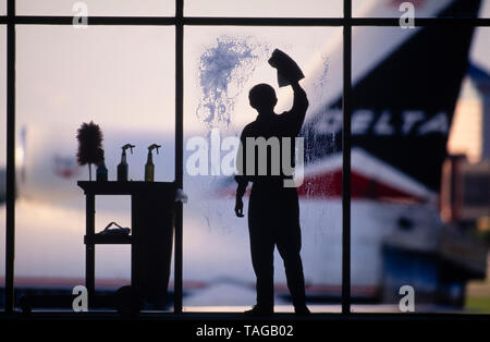 Un lavoratore di manutenzione pulisce windows all'Aeroporto Internazionale Hartsfield Jackson con aeromobili in background. Foto Stock