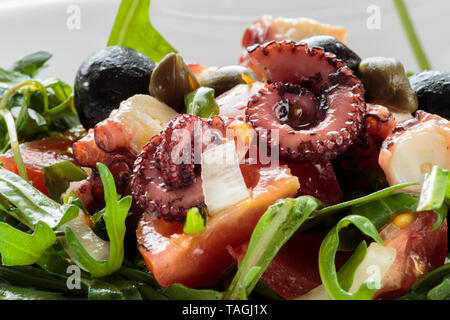 Insalata di polipo con rucola e olive su piastra bianca Foto Stock