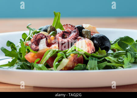 Insalata di polipo con rucola, olive e formaggio feta sulla piastra bianca Foto Stock