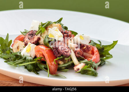 Insalata di polipo con rucola, olive e formaggio feta sulla piastra bianca Foto Stock