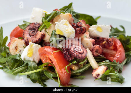 Insalata di polipo con rucola, olive e formaggio feta sulla piastra bianca Foto Stock