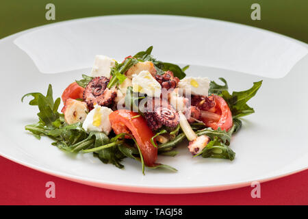 Insalata di polipo con rucola, olive e formaggio feta sulla piastra bianca Foto Stock